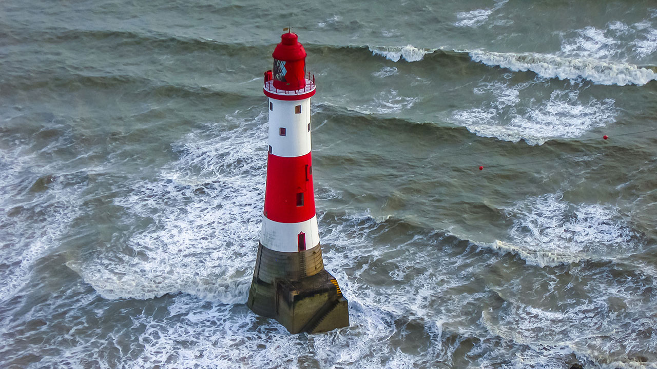 rotweißer Leuchtturm vor unruhiger See